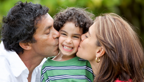 mother and father kissing son on each cheek