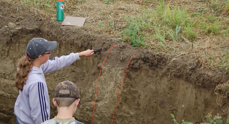 two youth identifying layers of soil in land judging competition