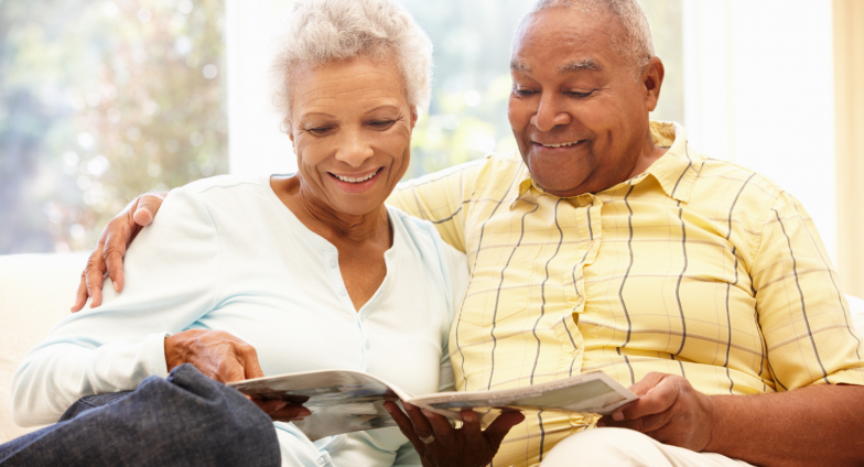 older adult couple reading magazine on couch