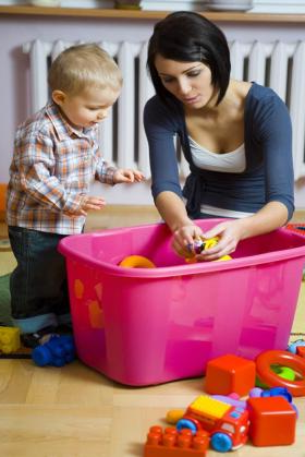 mother showing young toddler how to play with a toy